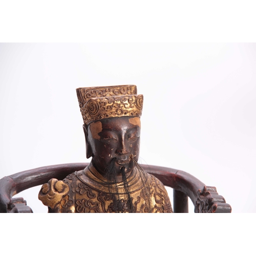 216 - A 19TH CENTURY ORIENTAL SEATED CARVED WOOD BUDHA with finely carved gilt scrollwork costume and head... 