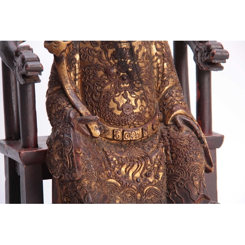 216 - A 19TH CENTURY ORIENTAL SEATED CARVED WOOD BUDHA with finely carved gilt scrollwork costume and head... 