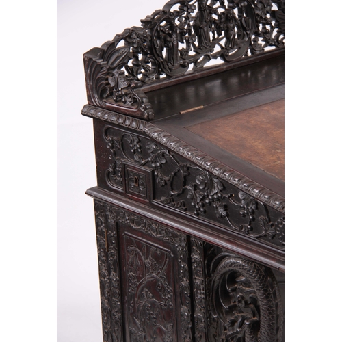 224 - A 19TH CENTURY CARVED HARDWOOD DAVENPORT with carved figural gallery above an angled leather writing... 