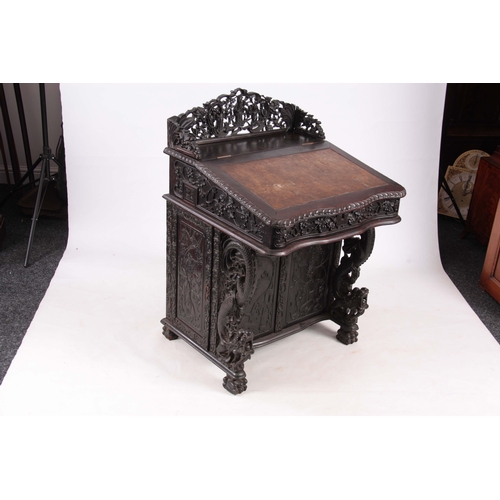 224 - A 19TH CENTURY CARVED HARDWOOD DAVENPORT with carved figural gallery above an angled leather writing... 