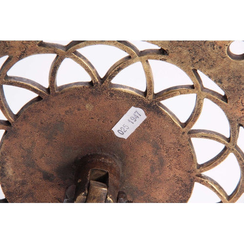 345 - AN 18TH CENTURY BRASS TRIVET with pierced cut out circular tilt-top above a turned stem and tripod b... 