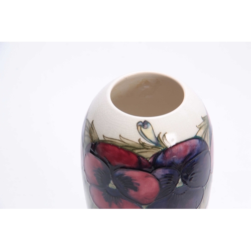 50 - A MOORCROFT TAPERING SHOULDERED VASE decorated with leafing different coloured pansy sprays on a cre... 