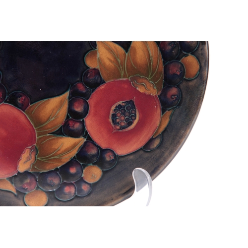 64 - AN EARLY 20th CENTURY MOORCROFT PLATE with pomegranate design, signed and impressed marks to the und... 