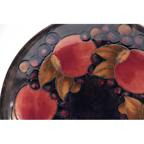 64 - AN EARLY 20th CENTURY MOORCROFT PLATE with pomegranate design, signed and impressed marks to the und... 