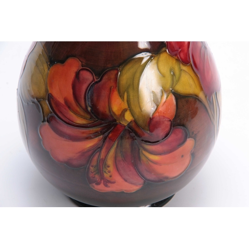 65 - A WALTER MOORCROFT FLAMBE BALUSTER VASE with colourful tube lined Hibiscus flower head and leaf spra... 