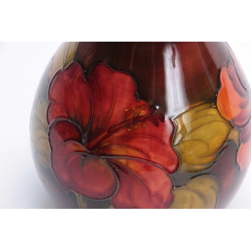 65 - A WALTER MOORCROFT FLAMBE BALUSTER VASE with colourful tube lined Hibiscus flower head and leaf spra... 