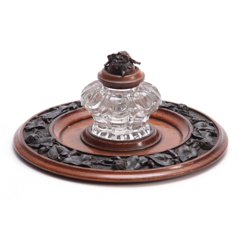 361 - A 19TH CENTURY CARVED OAK CIRCULAR INK STAND with cut glass inkwell to the centre having a floral ca... 