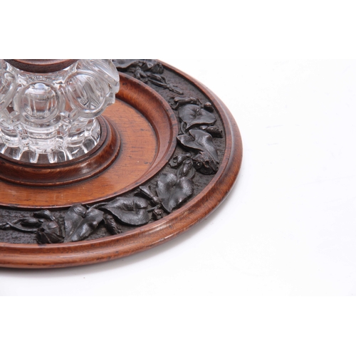 361 - A 19TH CENTURY CARVED OAK CIRCULAR INK STAND with cut glass inkwell to the centre having a floral ca... 