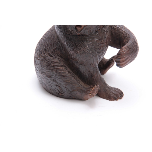 367 - A 19TH CENTURY SWISS CARVED BLACK FOREST SEATED BEAR INKWELL with hinged lid and arm outstretched fo... 