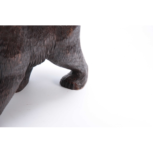 374 - A LATE 19TH CENTURY SWISS BLACK FOREST CARVED BEAR with glass eyes 46cm wide.