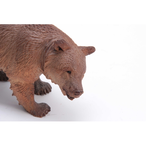 389 - A 19TH CENTURY SWISS BLACK FOREST CARVED BEAR IN THE MANNER OF HUGGLAR with glass eyes 22.5cm wide.