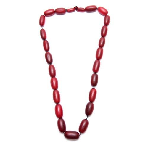 406 - A RED STAINED HORN GRADUATED STRING OF ELONGATED ROUNDED BEADS 64cm overall