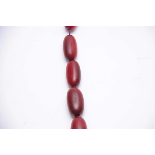 406 - A RED STAINED HORN GRADUATED STRING OF ELONGATED ROUNDED BEADS 64cm overall