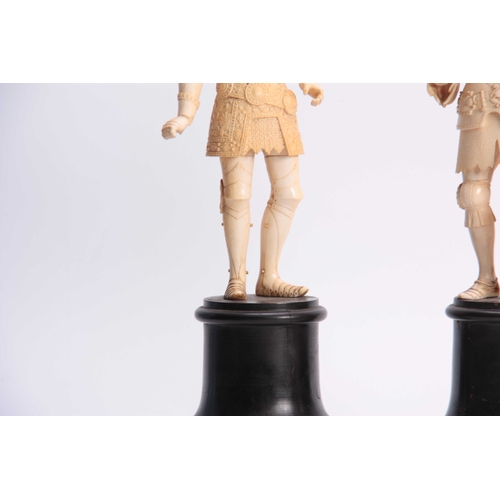 483 - A PAIR OF 19th CENTURY CARVED IVORY FIGURES modelled as knights in armour standing on turned ebonize... 