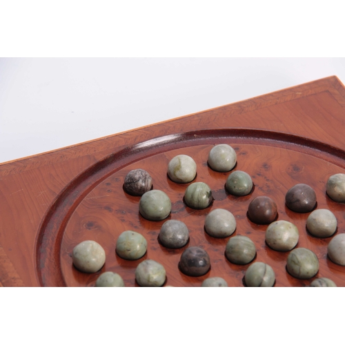 531 - A 19TH CENTURY HERRING-BANDED YEW-WOOD SOLITAIRE BOARD with green marbles; standing on small brass f... 