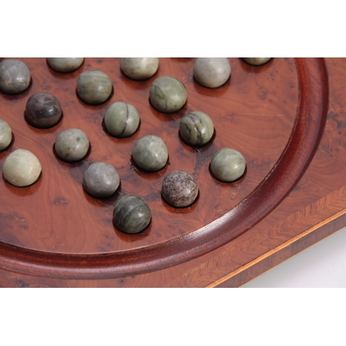 531 - A 19TH CENTURY HERRING-BANDED YEW-WOOD SOLITAIRE BOARD with green marbles; standing on small brass f... 