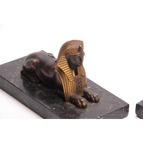 550 - A PAIR OF LATE 19TH CENTURY REGENCY STYLE BRONZE AND GILT BRONZE SPHINX BOOKENDS mounted on black ma... 