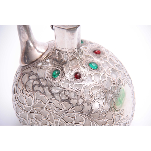 567 - A 19TH CENTURY JEWELLED AND BRIGHT CUT SILVER FILIGREE OVERLAID GLASS CLARET JUG of flattened ovoid ... 