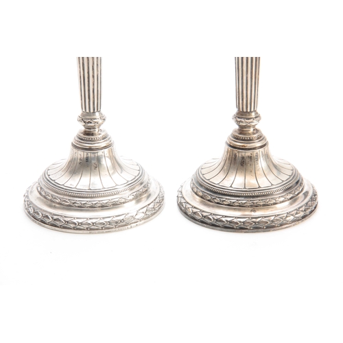 568 - A PAIR OF GERMAN SILVER CANDLESTICKS having reeded columns and fluted circular bases with acanthus l... 