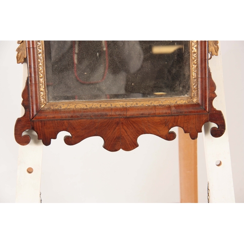 1032 - A GEORGE II WALNUT HANGING MIRROR with shaped fret cut surround having gilt carved crest and leaf wo... 