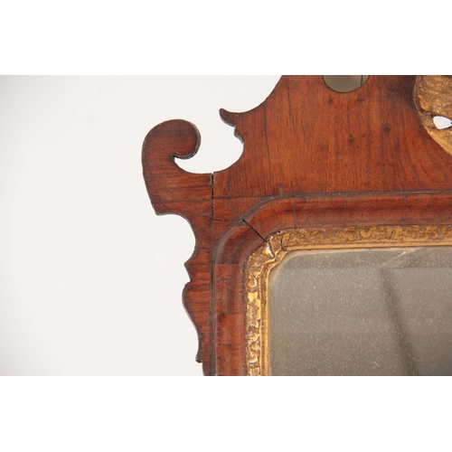 1032 - A GEORGE II WALNUT HANGING MIRROR with shaped fret cut surround having gilt carved crest and leaf wo... 