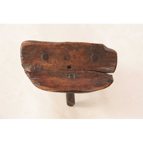 1036 - AN EARLY PRIMITIVE  WALNUT MILKING STOOL with dished seat, standing on three branch legs 41cm wide 2... 