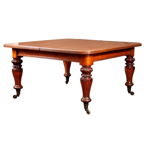 1094 - A 19TH CENTURY OAK EXTENDING DINING TABLE with three extra leaves; standing on leaf carved turned le... 