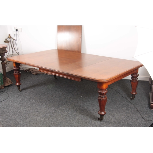 1094 - A 19TH CENTURY OAK EXTENDING DINING TABLE with three extra leaves; standing on leaf carved turned le... 