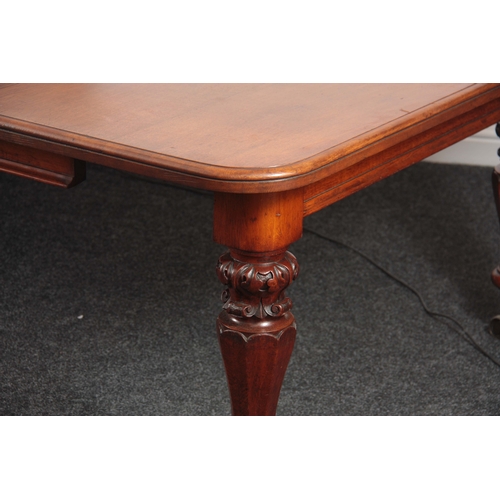 1094 - A 19TH CENTURY OAK EXTENDING DINING TABLE with three extra leaves; standing on leaf carved turned le... 