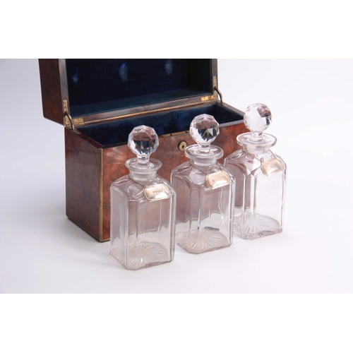 923 - A 19TH CENTURY FIGURED WALNUT BRASS BOUND DECANTER BOX fitted with three cut glass decanters and sto... 