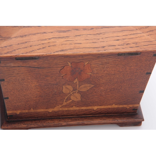 953 - AN ARTS AND CRAFT INLAID OAK TEA CADDY of tapered form with moulded hinged top above a floral inlaid... 