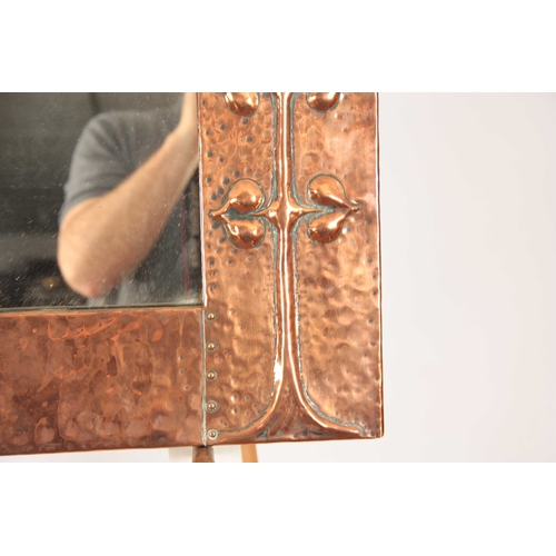 961 - AN ARET NOVEAU HAMMERED COPPER HANGING MIRROR with relief moulded stylised flowers 69cm wide 52cm hi... 