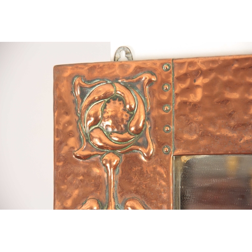 961 - AN ARET NOVEAU HAMMERED COPPER HANGING MIRROR with relief moulded stylised flowers 69cm wide 52cm hi... 