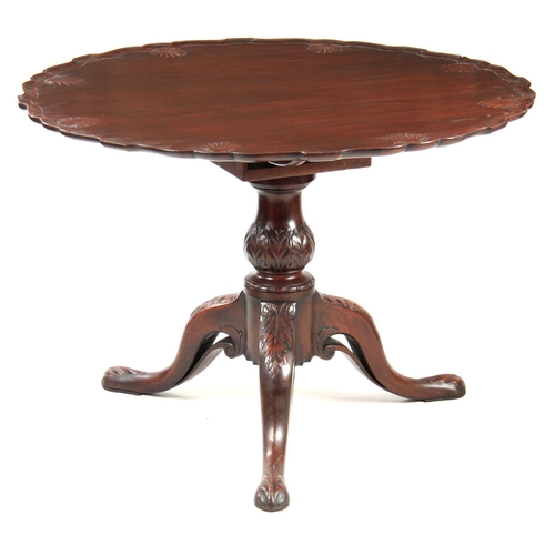 985 - A GEORGE III MAHOGANY IRISH TILT-TOP TABLE with dished scallop edge top carved with shells, above a ... 