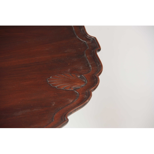 985 - A GEORGE III MAHOGANY IRISH TILT-TOP TABLE with dished scallop edge top carved with shells, above a ... 