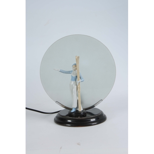 64 - A 1930'S ART DECO CONTINENTAL LAMP mounted with a porcelain figure of a skier having a circular fros... 