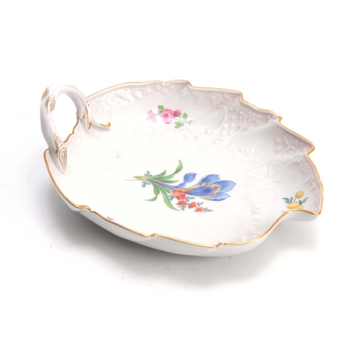 82 - A 19TH CENTURY MEISSEN LEAF SHAPED DISH decorated with painted flowers, having a branch work handle ... 