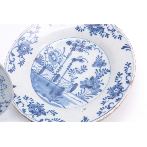 83 - FOUR 18TH CENTURY DELFT BLUE AND WHITE PLATES decorated with floral designs 23cm diameter.