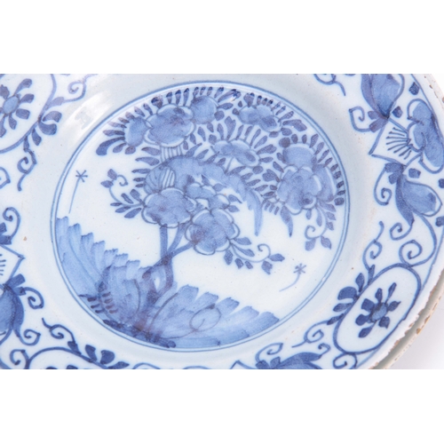 83 - FOUR 18TH CENTURY DELFT BLUE AND WHITE PLATES decorated with floral designs 23cm diameter.