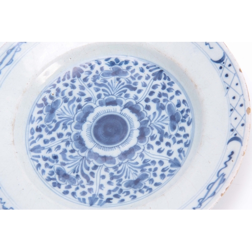 83 - FOUR 18TH CENTURY DELFT BLUE AND WHITE PLATES decorated with floral designs 23cm diameter.