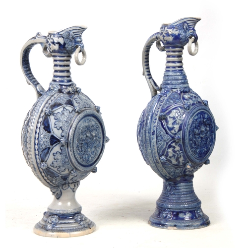 89 - A PAIR OF 19TH CENTURY GERMAN WESTERWALD SALT GLAZED EWERS the large rounded bodies with relief moul... 