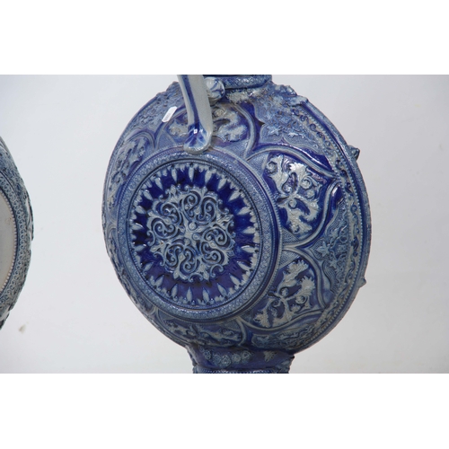 89 - A PAIR OF 19TH CENTURY GERMAN WESTERWALD SALT GLAZED EWERS the large rounded bodies with relief moul... 