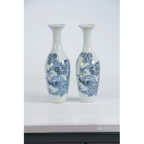 148 - A SLENDER PAIR OF SMALL 18TH / 19TH CENTURY BLUE AND WHITE VASES decorated with dragons 20cm high.