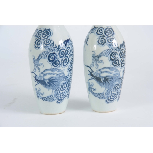 148 - A SLENDER PAIR OF SMALL 18TH / 19TH CENTURY BLUE AND WHITE VASES decorated with dragons 20cm high.