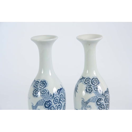 148 - A SLENDER PAIR OF SMALL 18TH / 19TH CENTURY BLUE AND WHITE VASES decorated with dragons 20cm high.