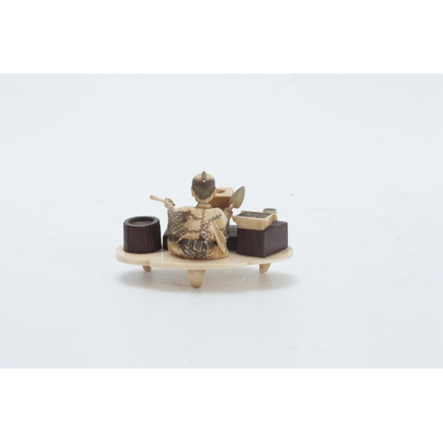 199 - A JAPANESE MEIJI PERIOD IVORY AND STAINED IVORY OKIMONO the seated figure modelled as a brickmaker w... 