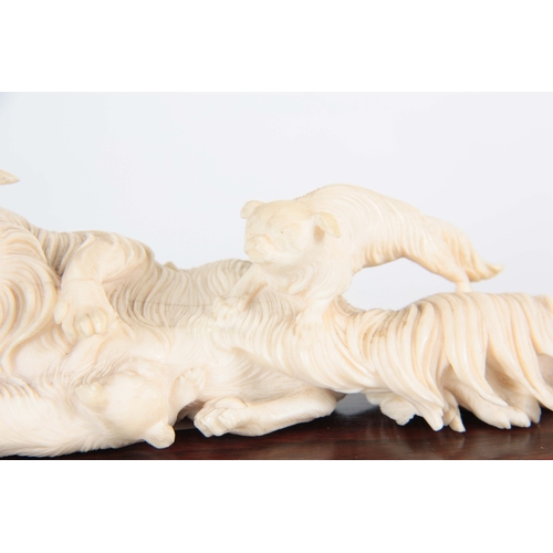 200 - A LATE 19TH / EARLY 20TH CENTURY CHINESE CARVED IVORY SCULPTURE depicting a reclining dog with two p... 