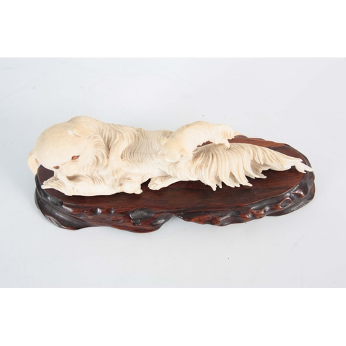 200 - A LATE 19TH / EARLY 20TH CENTURY CHINESE CARVED IVORY SCULPTURE depicting a reclining dog with two p... 