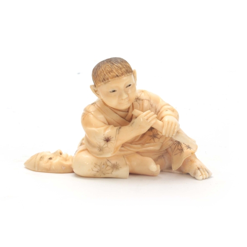 206 - A JAPANESE CARVED IVORY OKIMONO modelled as a young seated boy holding a chisel making a Noh mask 5c... 