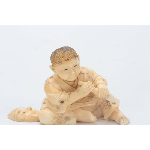 206 - A JAPANESE CARVED IVORY OKIMONO modelled as a young seated boy holding a chisel making a Noh mask 5c... 